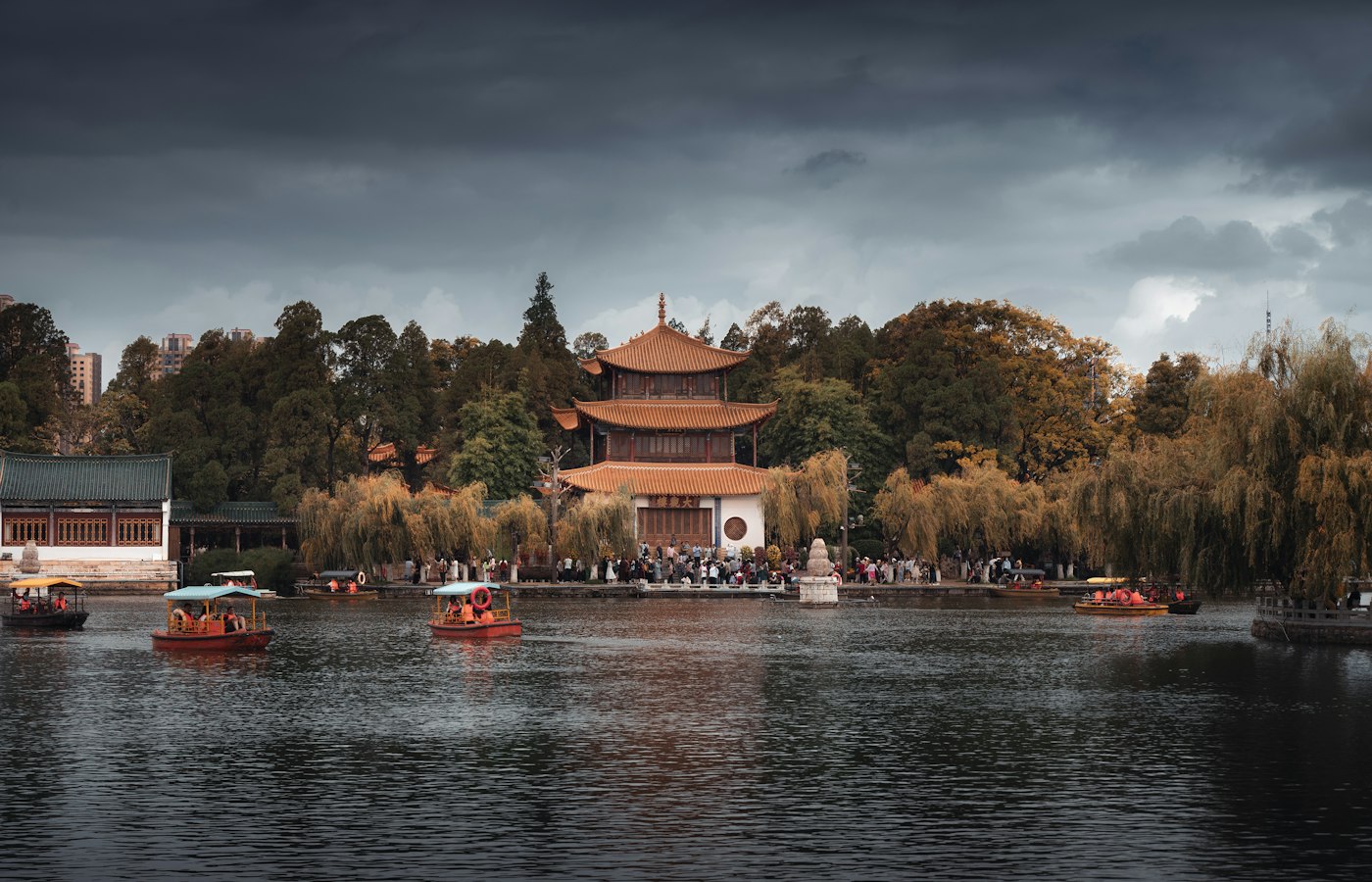 A traditional pavilion behind willow trees on a lake in Kunming